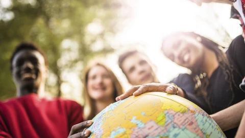 Multiple people with their hands on a globe